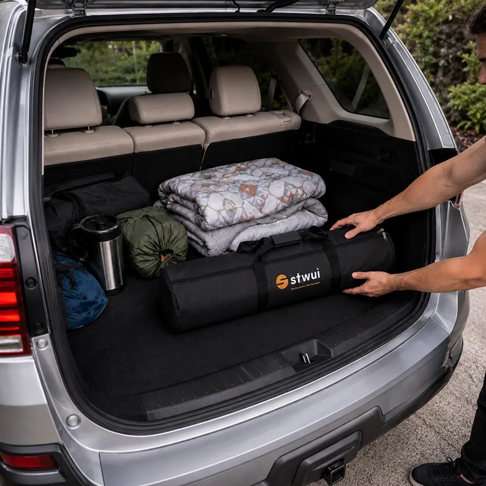 STWUI projector screen carry bag being loaded into an SUV trunk alongside camping gear